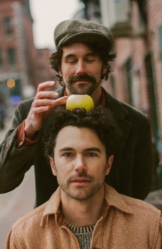 Tim holding a lemon above Paul's head on a city street.